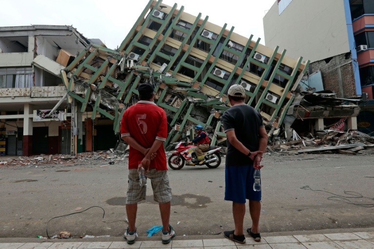 Deux hommes regardent un immeuble d&eacute;truit &agrave; Portoviejo, en Equateur, le 21 avril 2016, une semaine apr&egrave;s le violent s&eacute;isme qui a ravag&eacute; le pays. &copy; AFP
